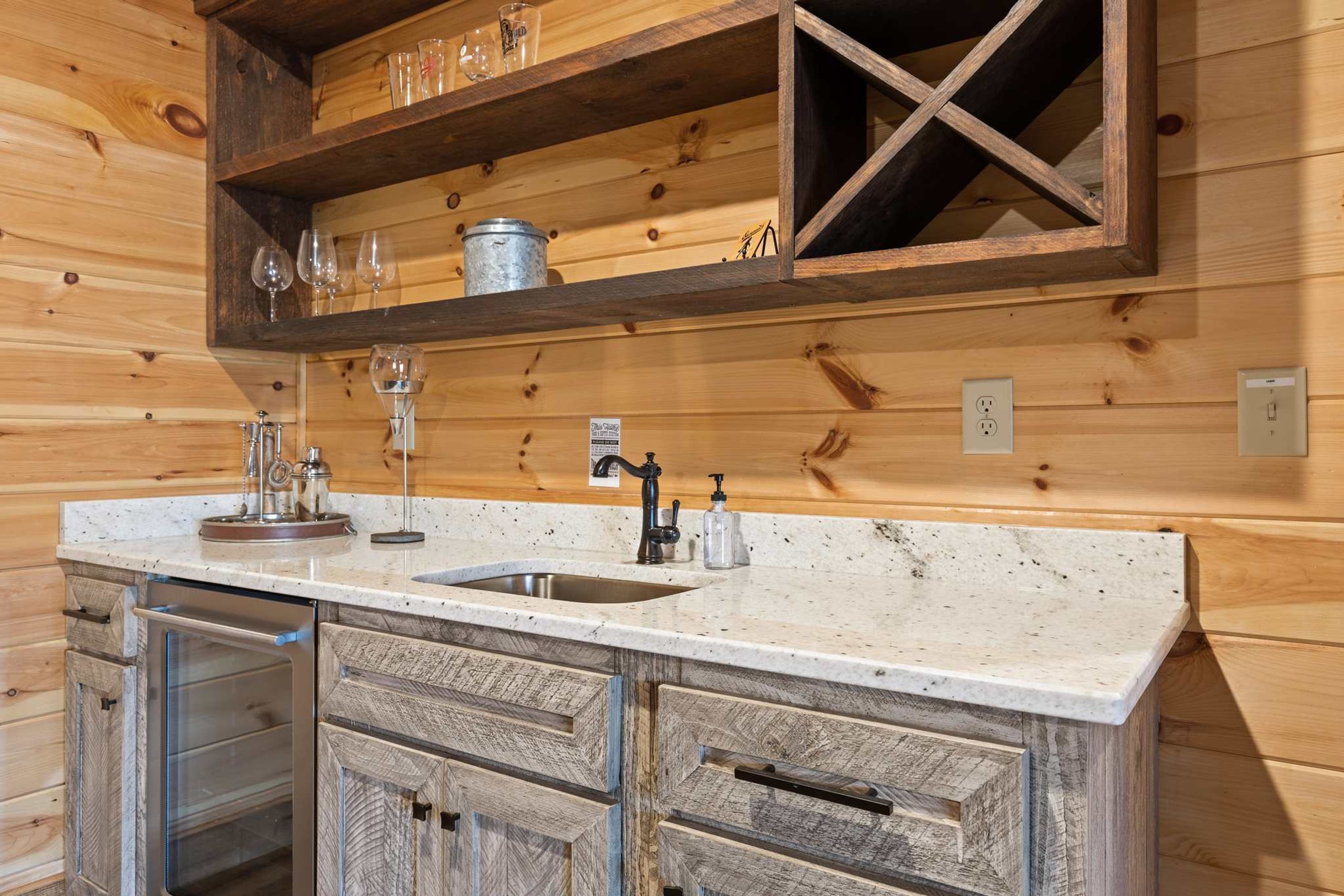 A kitchen with a wooden countertop, a sink, and a built-in wine rack above it.