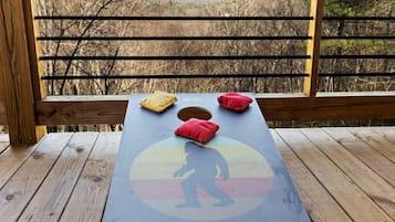 A wooden deck with a table featuring a colorful design and cushions.