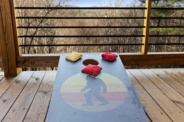 A wooden deck with a table featuring a colorful design and cushions. - Stunning Views Sleeps 10 - Hot Tub - 2 Fireplaces (Blue Ridge)