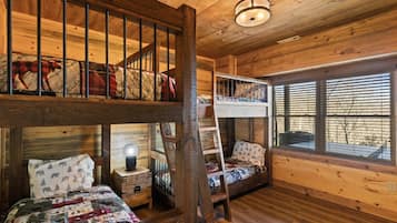 A cabin with a loft bed, a lower bunk bed, and a desk with a lamp.