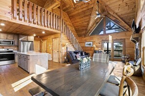 A spacious wooden cabin interior with a kitchen, dining area, and a loft bedroom. - Stunning Views Sleeps 10 - Hot Tub - 2 Fireplaces (Blue Ridge)