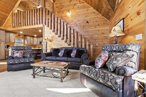 A log cabin interior with a staircase, two sofas, a coffee table, and a lamp. - Stunning Views Sleeps 10 - Hot Tub - 2 Fireplaces (Blue Ridge)