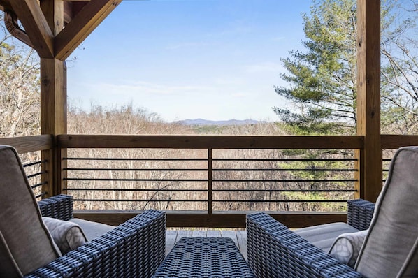 A covered outdoor seating area with wicker furniture and a view of a natural landscape. - Stunning Views Sleeps 10 - Hot Tub - 2 Fireplaces (Blue Ridge)