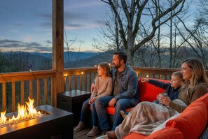 A family on a wooden deck with a fire feature, overlooking a mountainous landscape. - Mountain Retreat - Sauna - Hot Tub - Fire Pit (Asheville)