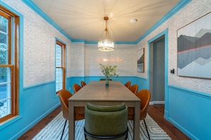 A dining area with a wooden table, six chairs, a vase with greenery, and a chandelier. - Mountain Retreat - Sauna - Hot Tub - Fire Pit (Asheville)
