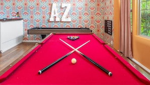 A pool table with a red felt surface, two pool cues, and a cue ball. - Pickleball Heated Pool Spa Sleeps 16 (Peoria)