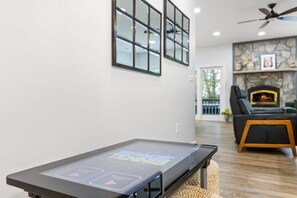 A modern living room with a fireplace, a ceiling fan, and a coffee table with a digital interface. - 12 Min to Downtown Sleeps 12 Hot Tub Fire Pit (Blue Ridge)