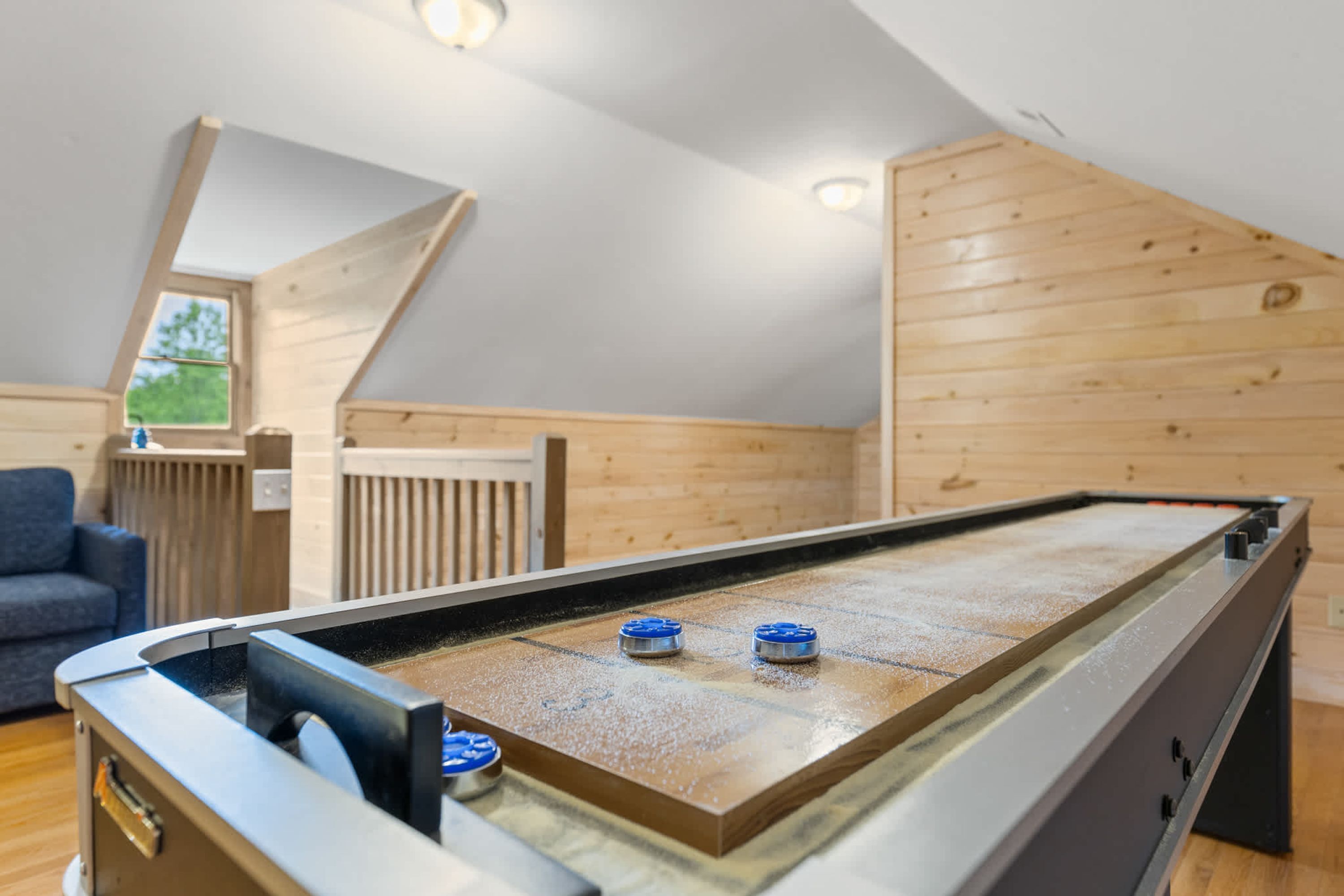 A room with a pool table, a blue sofa, and wooden paneling on the walls.