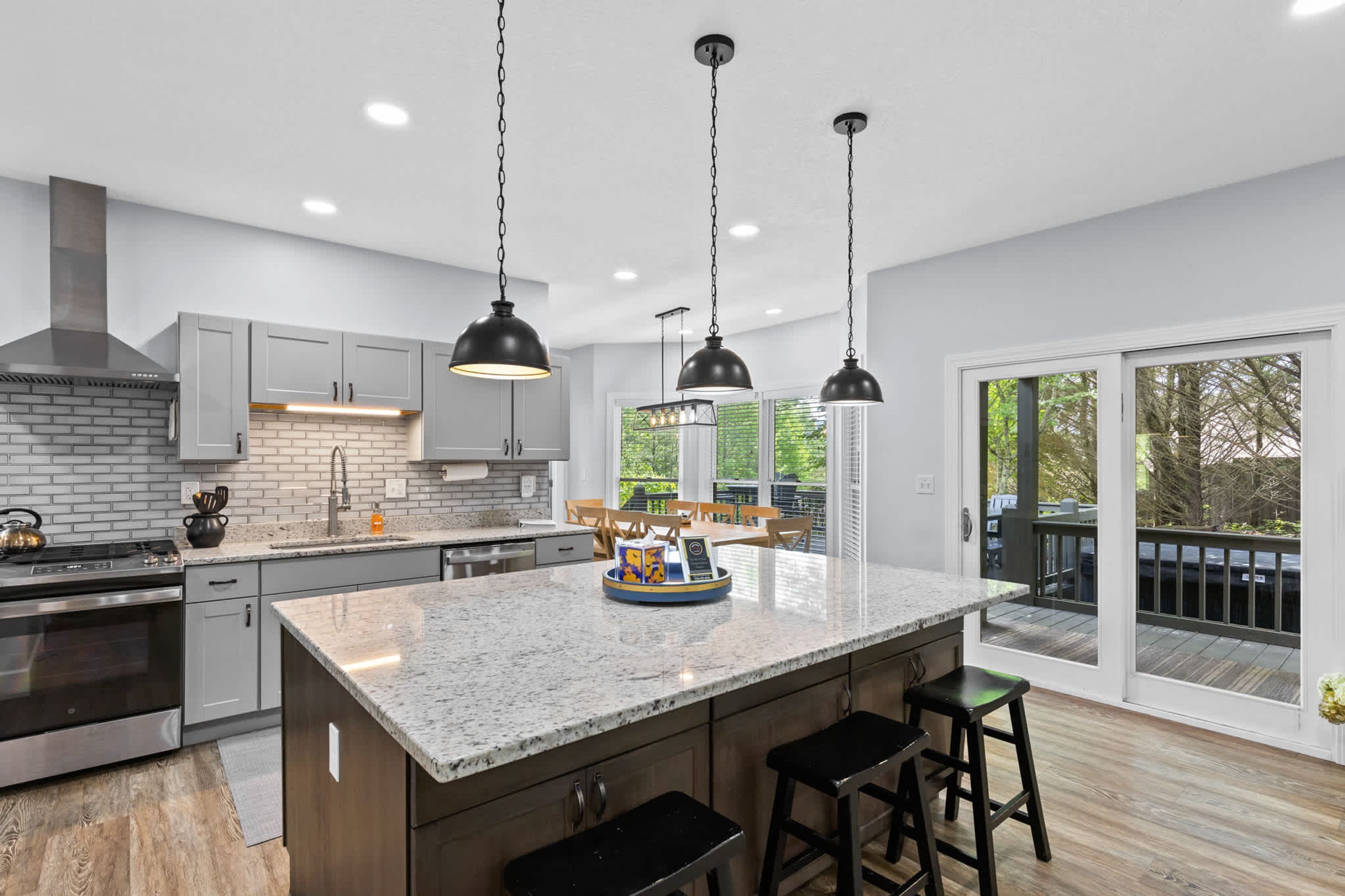 A modern kitchen with a large island, stainless steel appliances, and pendant lighting.
