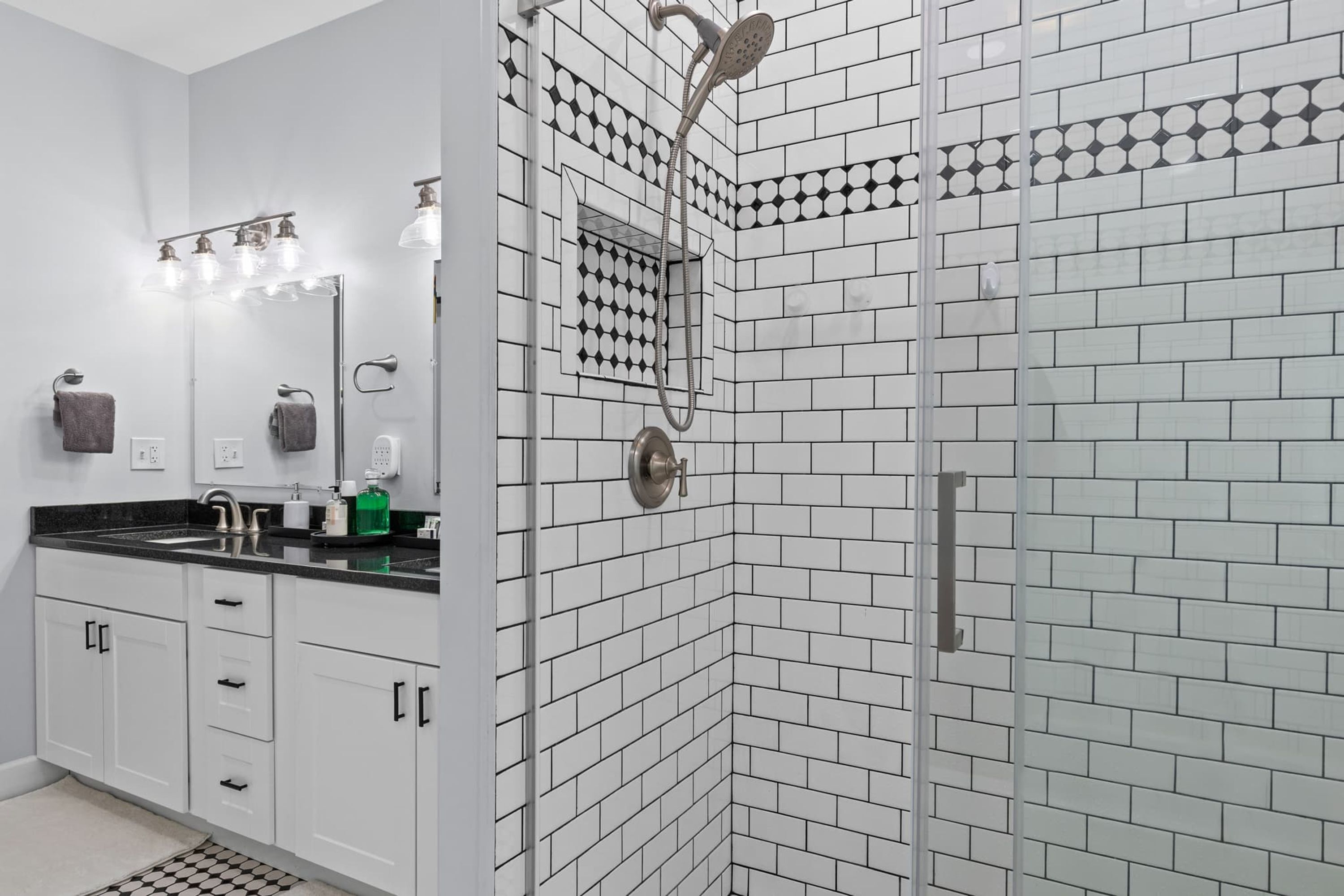 Een moderne badkamer met douche, wastafel met spiegel en toilet.