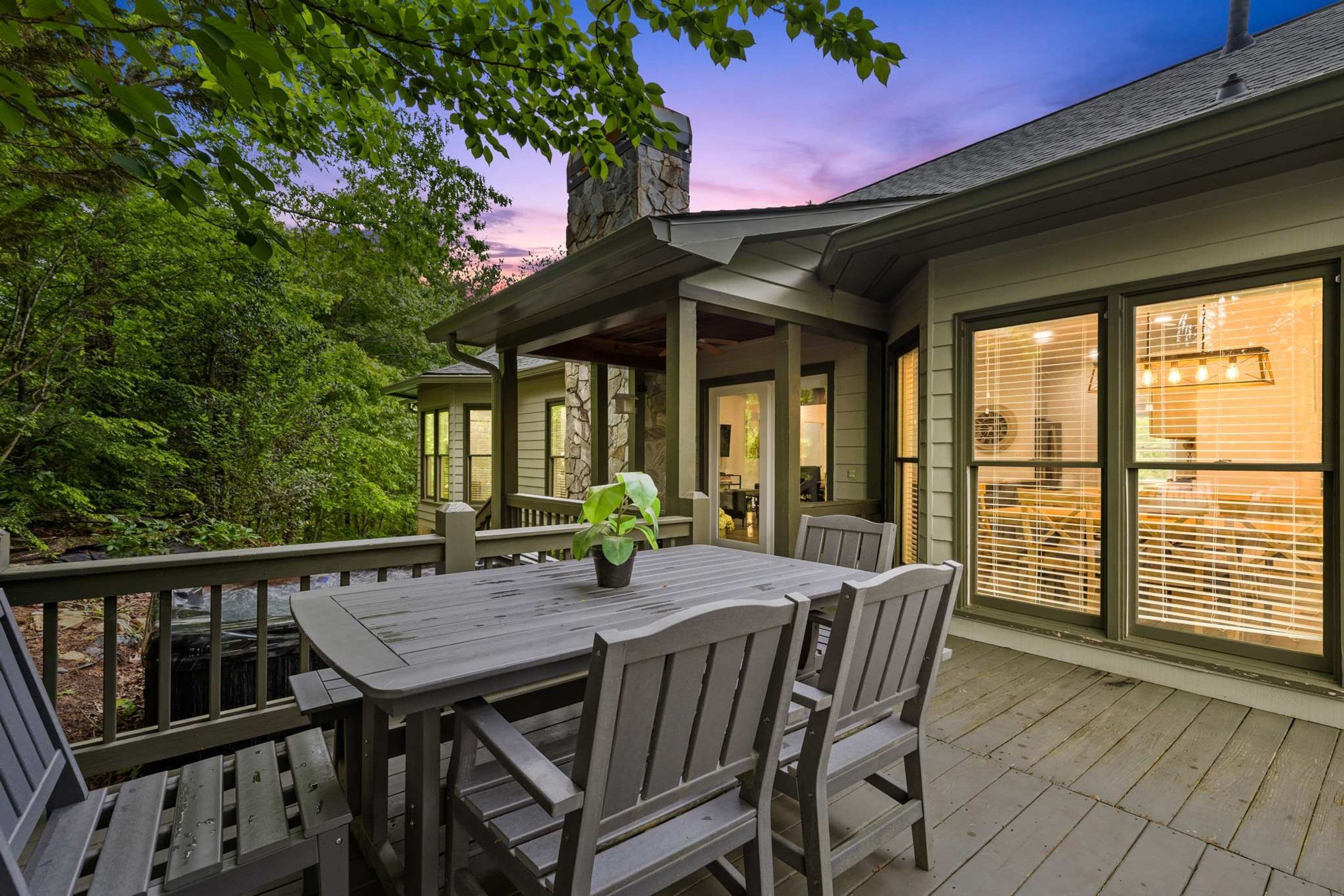 An outdoor patio with a table and chairs, surrounded by a wooden deck and a stone wall.