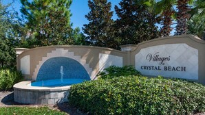 A sign for 'Villages of Crystal Beach' with a fountain and landscaped greenery. - Royal Palms Arcade Free Beach Shuttle Pool (Destin)