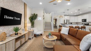 A modern living room with a sofa, a coffee table, and a TV mounted on the wall. - Royal Palms Arcade Free Beach Shuttle Pool (Destin)
