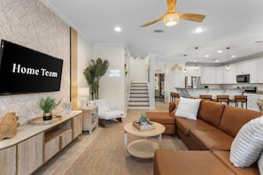 Ein modernes Wohnzimmer mit einer Couch, einem Couchtisch und einem an der Wand befestigten Fernseher.