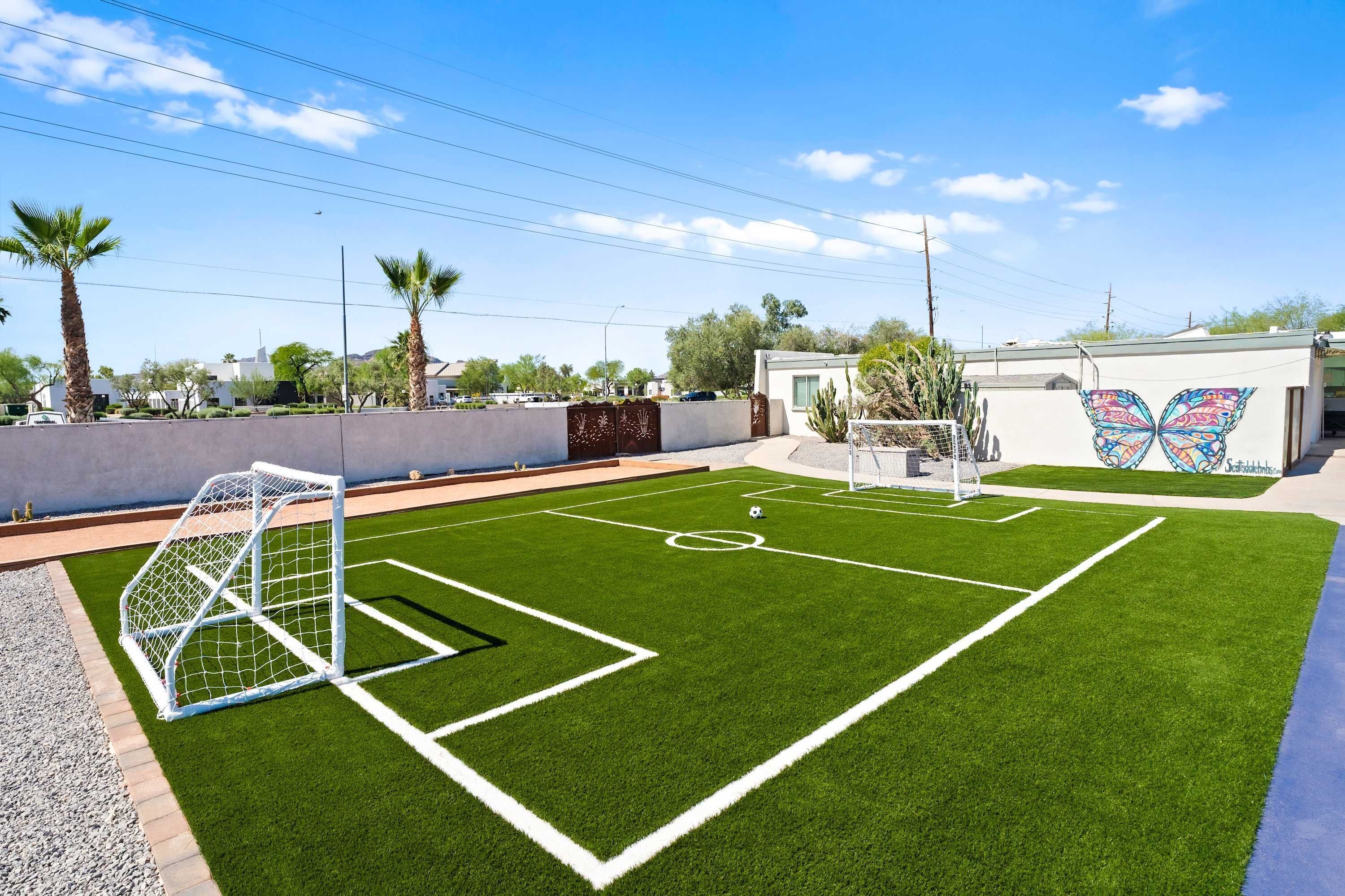 Un campo de fútbol con un arco, rodeado por un muro bajo y palmeras.