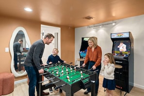 A room with a foosball table, a television, and a mirror. - Sonoran Grove Epic Yard With Two Pickleball Courts (Scottsdale)