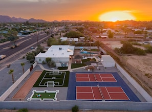 A residential area with a tennis court, a pool, and a house with a flat roof. - Sonoran Grove Epic Yard With Two Pickleball Courts (Scottsdale)