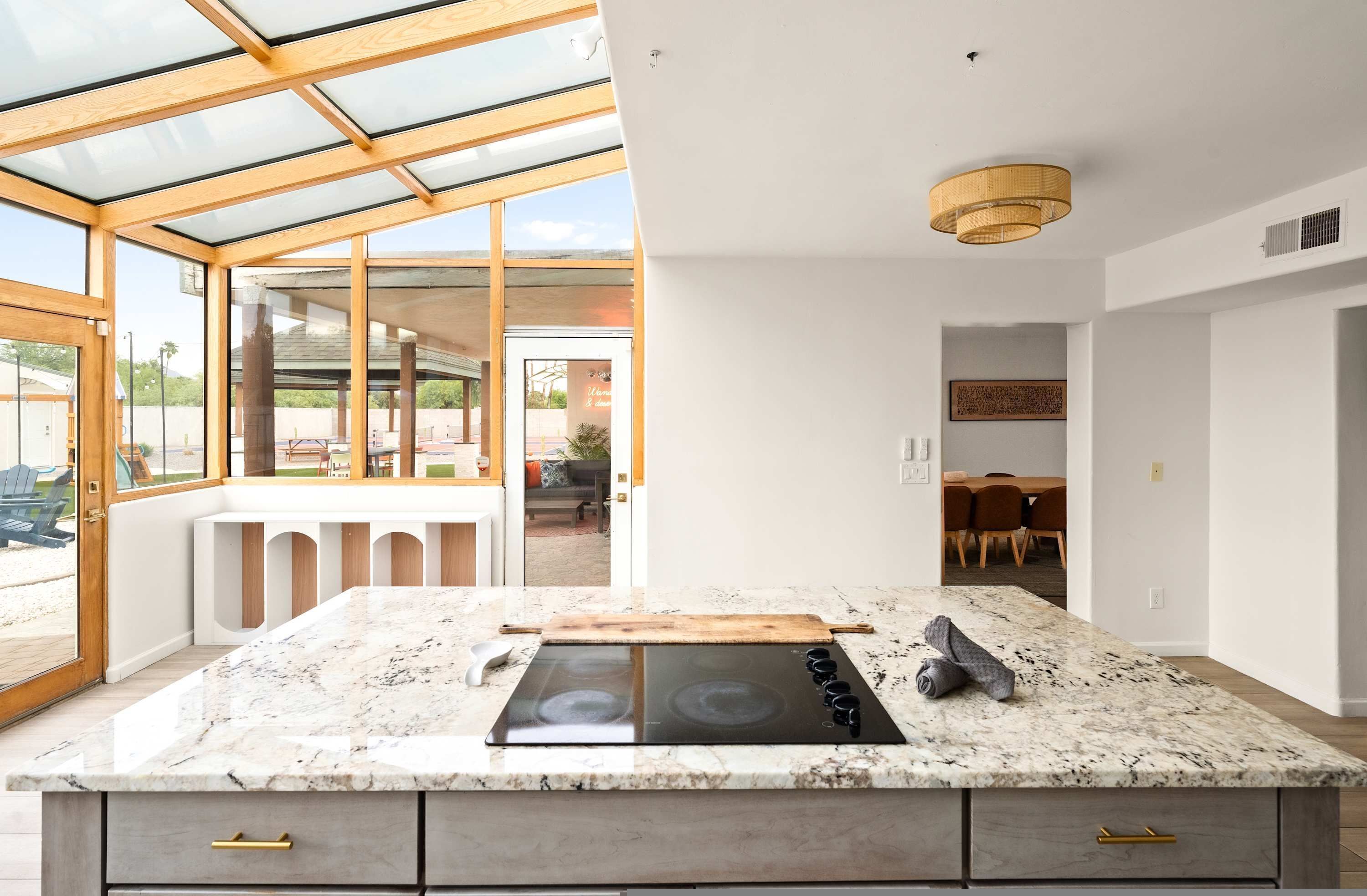 Een moderne keuken met glazen wanden, een inbouwfornuis en een eethoek met een tafel en stoelen.