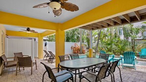 A covered patio area with a round table and chairs, a ceiling fan, and a view of a pool and greenery. - Holmes Beach - Pool - Minutes to Beach - Sleeps 8 (Holmes Beach)
