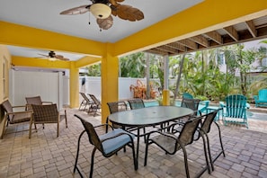 A covered patio area with a round table and chairs, a ceiling fan, and a view of a pool and greenery. - Holmes Beach - Pool - Minutes to Beach - Sleeps 8 (Holmes Beach)