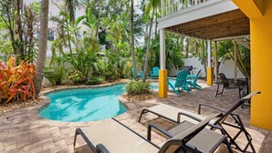 A pool area with lounge chairs, a covered seating area, and tropical vegetation. - Holmes Beach - Pool - Minutes to Beach - Sleeps 8 (Holmes Beach)