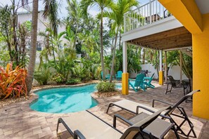 A pool area with lounge chairs, a covered seating area, and tropical vegetation. - Holmes Beach - Pool - Minutes to Beach - Sleeps 8 (Holmes Beach)