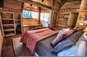 Ein Holzhäuschen im Inneren, mit einem Bett, einem Schreibtisch und einem Fenster.