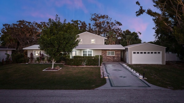 A two-story house with a garage, surrounded by trees and a well-maintained lawn. - Sleeps 16 Golf Simulator Pickleball Pool Spa (Bradenton)