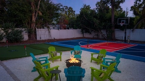 A backyard with a basketball court, a fire pit, and green Adirondack chairs. - Sleeps 16 Golf Simulator Pickleball Pool Spa (Bradenton)