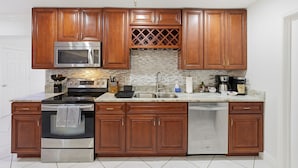A modern kitchen with wooden cabinets, stainless steel appliances, and a tiled backsplash. - Sleeps 16 Golf Simulator Pickleball Pool Spa (Bradenton)