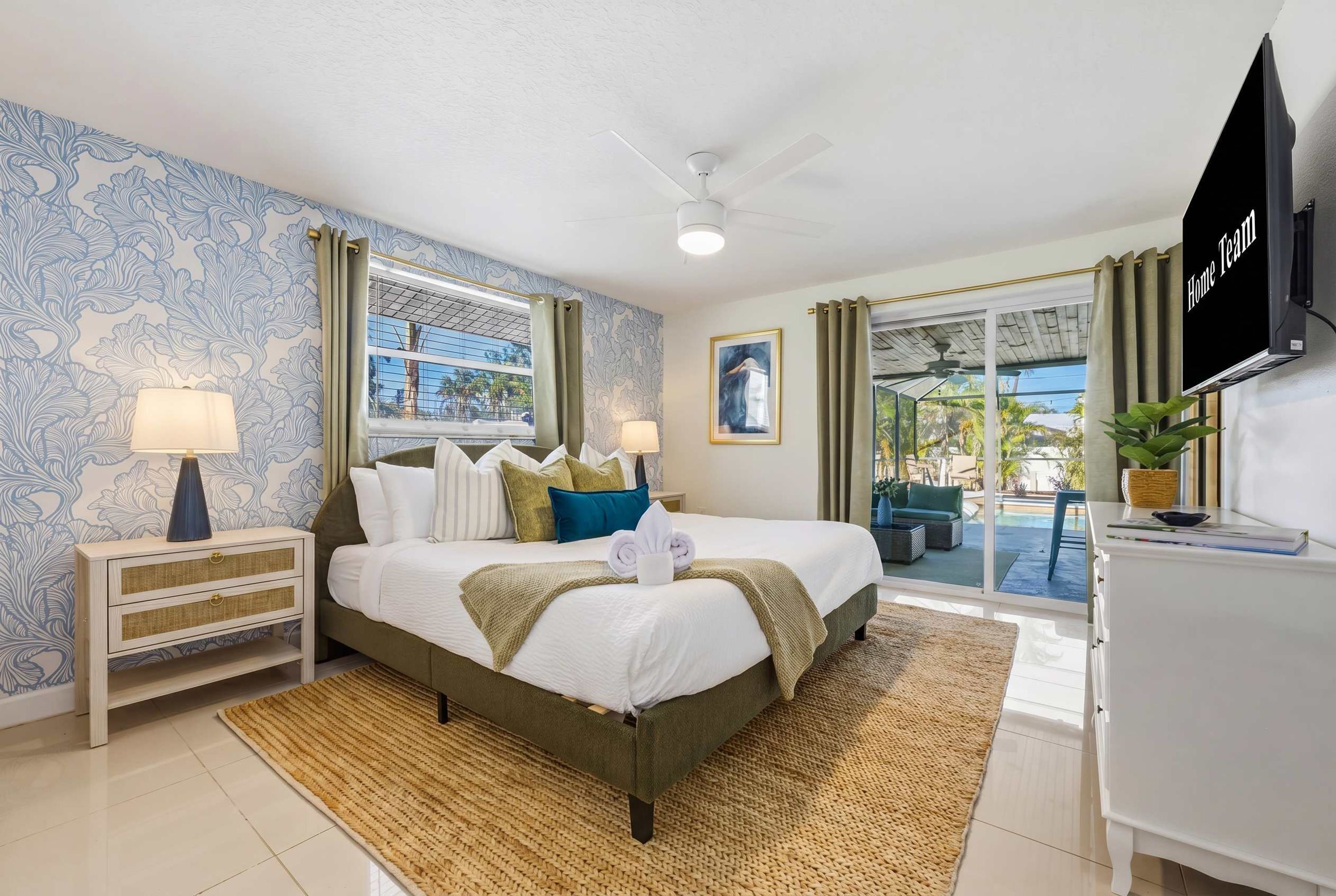 A hotel room with a bed, nightstands, a TV, and a view of the outdoors.