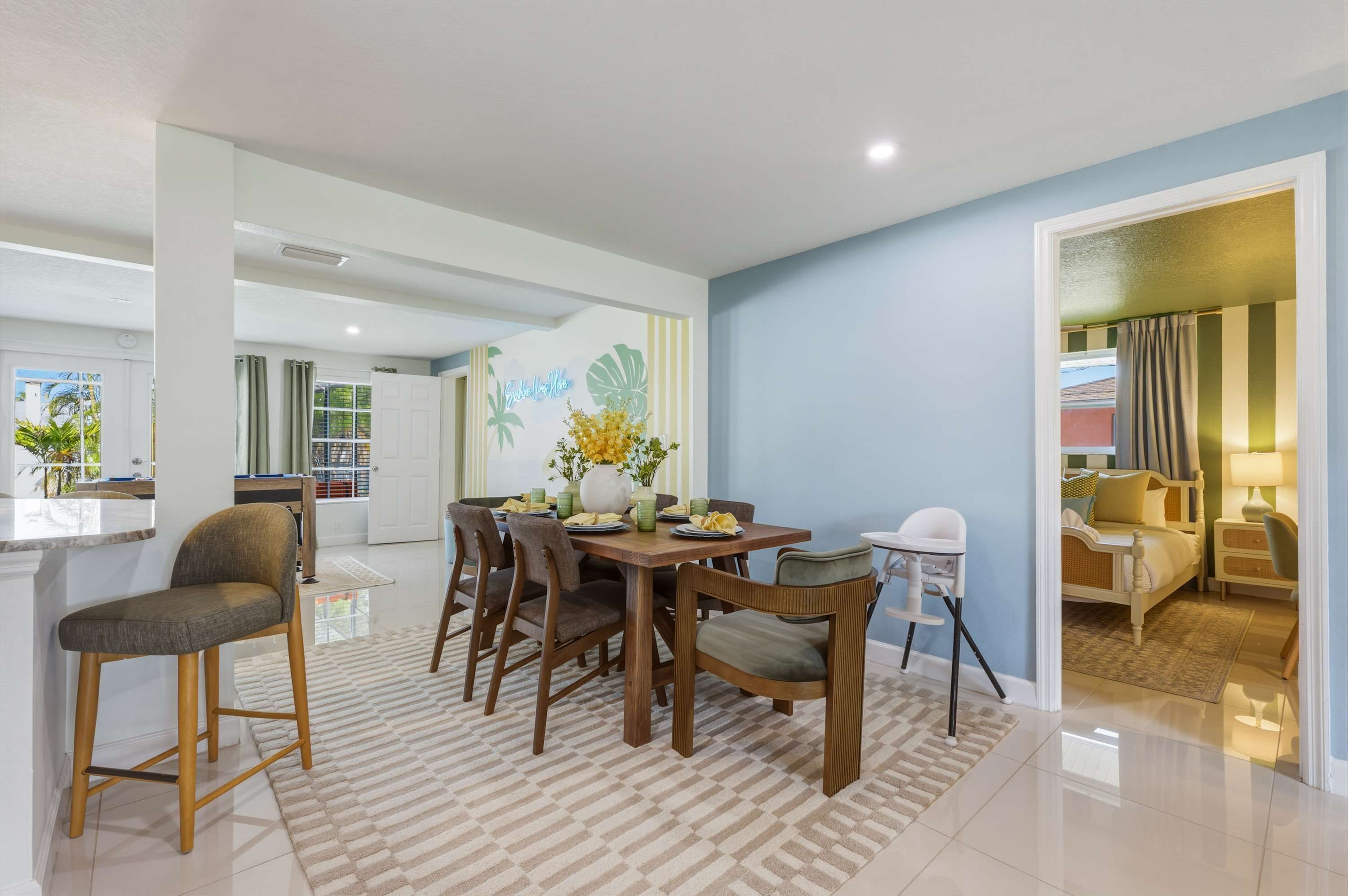 A modern dining area with a wooden table, chairs, and a vase of flowers.