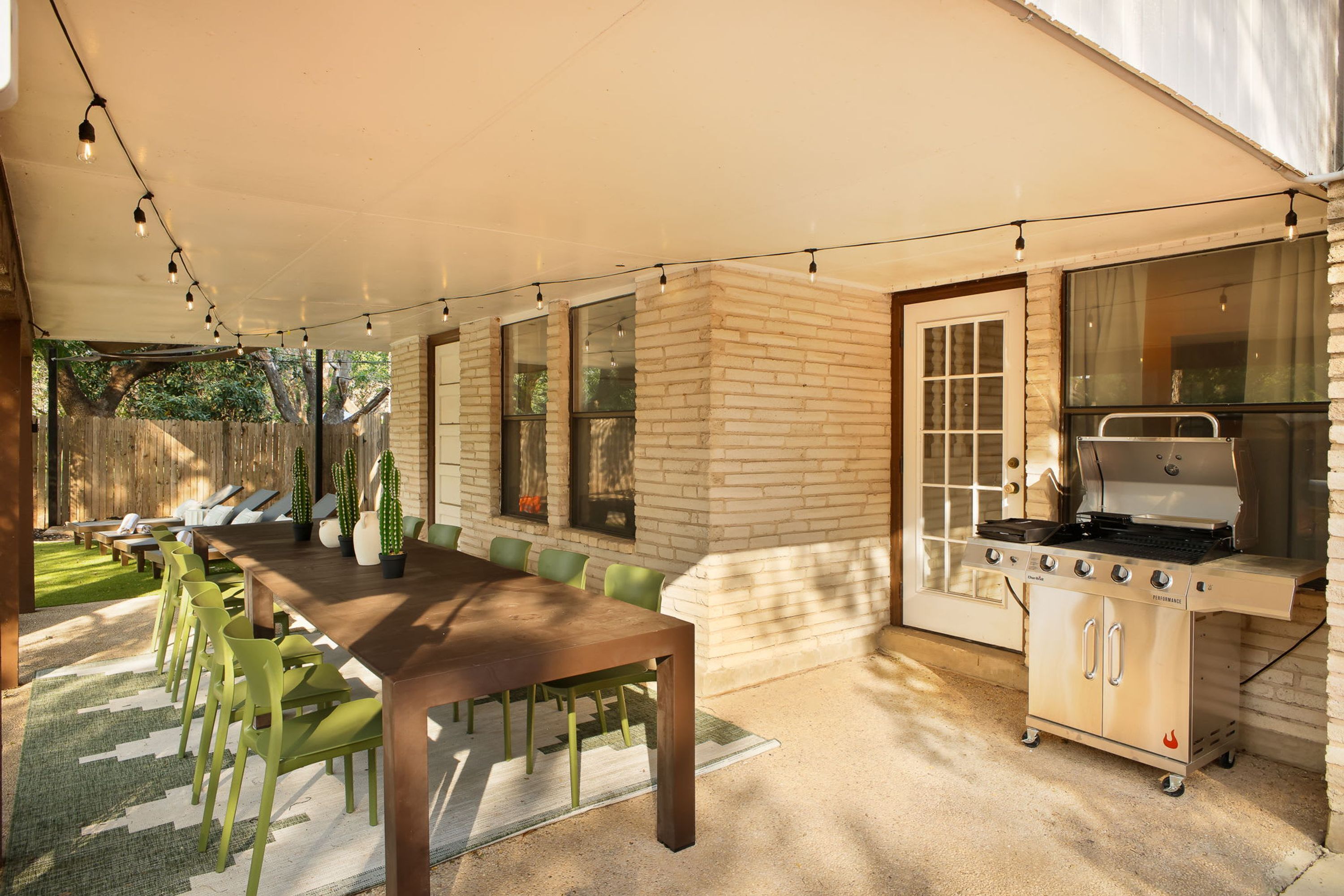 Une terrasse extérieure avec une table à manger, des chaises et un barbecue.