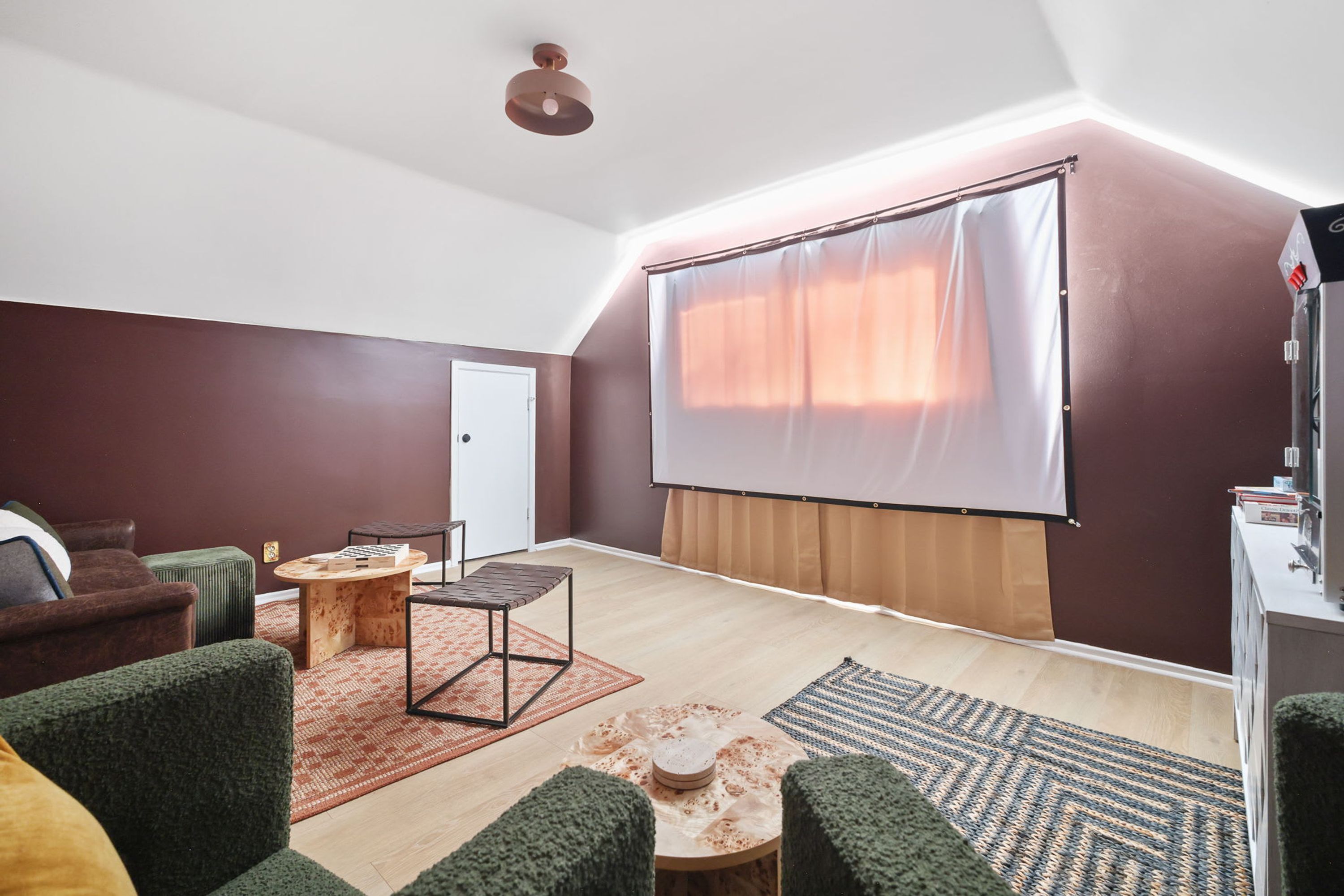 A living room with a ceiling fan, a projector screen, a sofa, a coffee table, and a television.