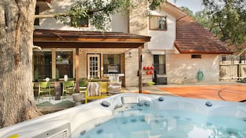 Ein Wohnhaus mit Whirlpool, Sitzgelegenheit im Freien und Grillplatz.