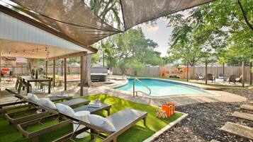 An outdoor patio area with a pool, lounge chairs, and a covered seating area.