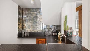 A modern kitchen with a dark countertop, a blender, and a cactus plant.
