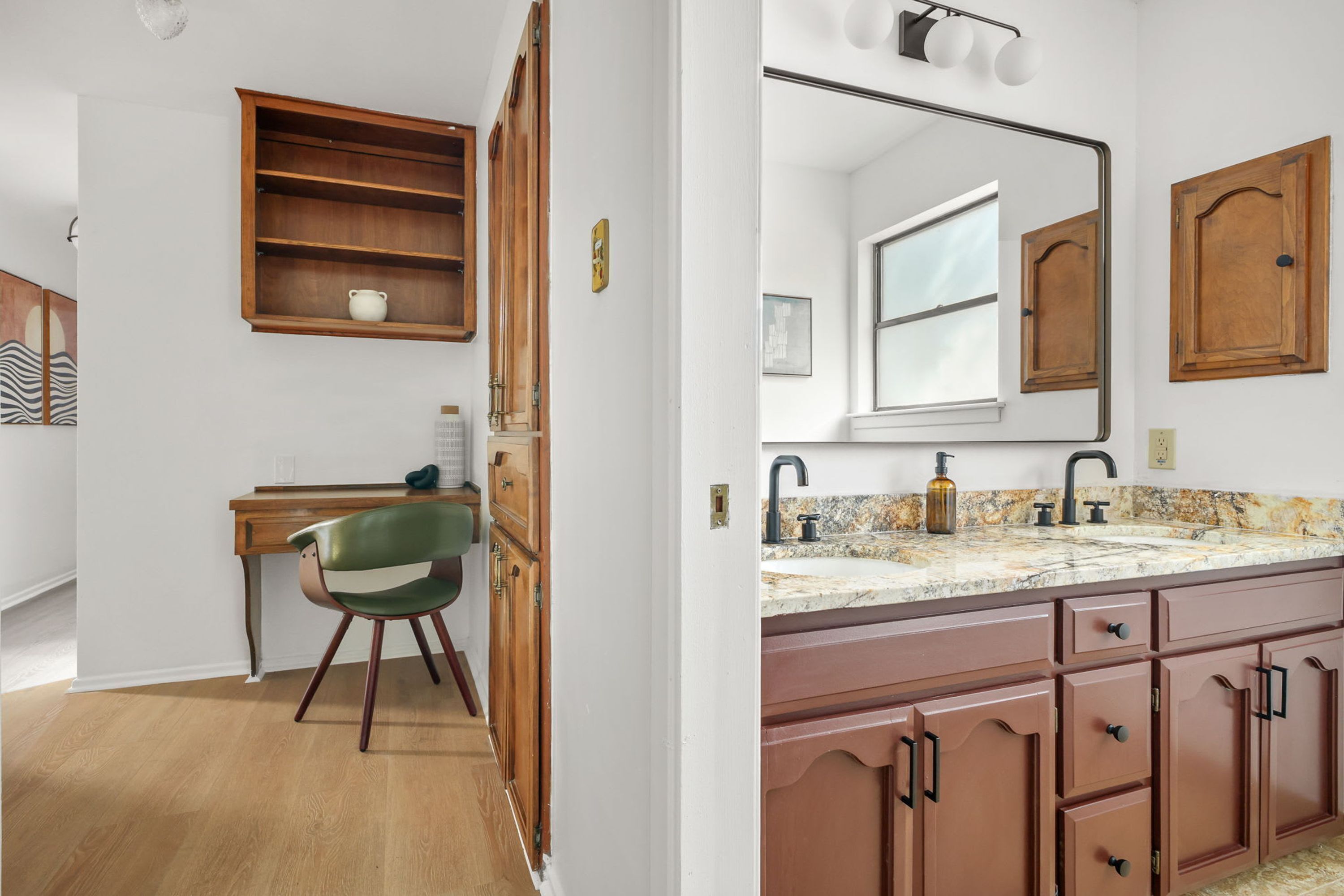 A room with a wooden desk, a chair, a wooden cabinet, a mirror, a sink, and a window.