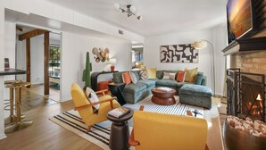 Ein geräumiges Wohnzimmer mit einem Ecksofa, einem Kamin und einer modernen Deckenleuchte.