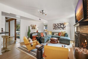 Ein geräumiges Wohnzimmer mit einem Ecksofa, einem Kamin und einer modernen Deckenleuchte.