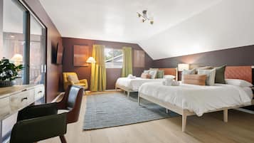 A modern bedroom with two beds, a desk, a chair, and a large window.
