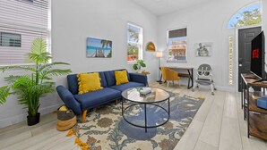 A modern living room with a sofa, coffee table, and a dining area with a chair and table. - Pineapple Paradise - 13 min to Beach - Fire Pit (Sarasota)