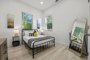 Ein Schlafzimmer mit einem Bett, zwei Nachttischen, einem Spiegel und Bildern an den Wänden.