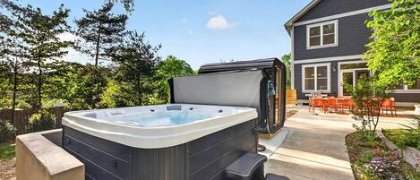 A hot tub in a backyard with a house in the background.
