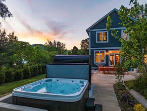Ein Haus mit Whirlpool im Vordergrund und einer Terrasse mit Gartenmöbeln.