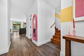 A modern interior with a wooden staircase, a hallway leading to a room, and a door with a pink frame. - Outdoor Games Hot Tub Firepit Grill Sauna (Asheville)