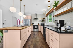 A modern kitchen with a central island, stainless steel appliances, and pendant lighting. - Outdoor Games Hot Tub Firepit Grill Sauna (Asheville)