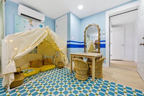 A room with a checkered floor, a bed with a canopy, a table, wicker chairs, and a mirror. - Palm Shell Villa - Pool - Pickleball - Hot Tub (Bradenton)