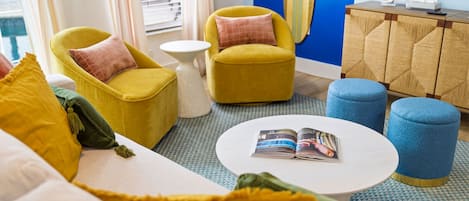 Una sala de estar moderna con sillones amarillos, una mesa de centro blanca y un reposapiés azul.