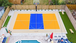 Een buitenbasketbalveld met een zwembad en een loungegedeelte.